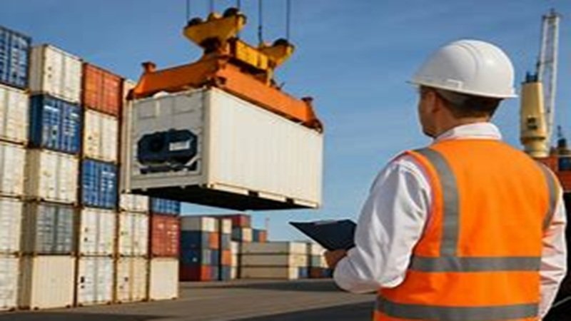 Inspector de ILC realizando inspección hidrobiológica, con overol blanco con líneas celestes/azules/naranjas, chaleco de seguridad naranja y casco blanco.
